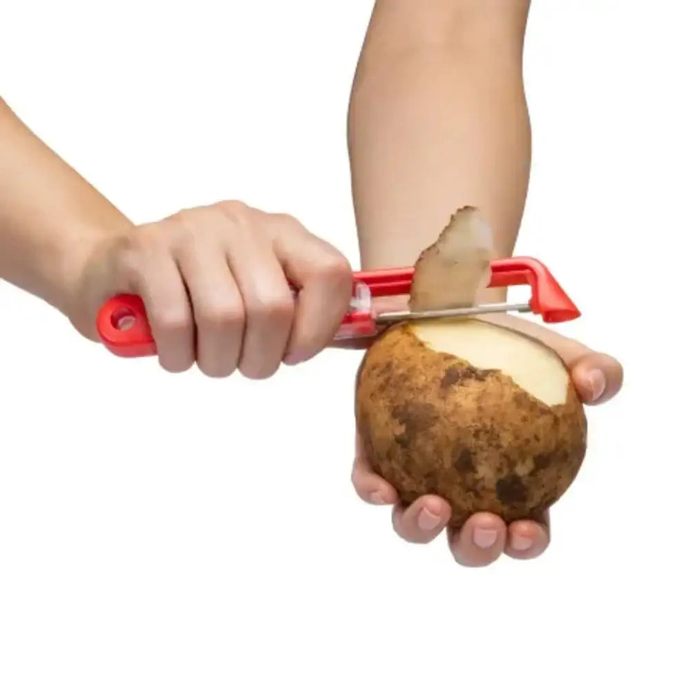 Person using a red potato peeler on a white background