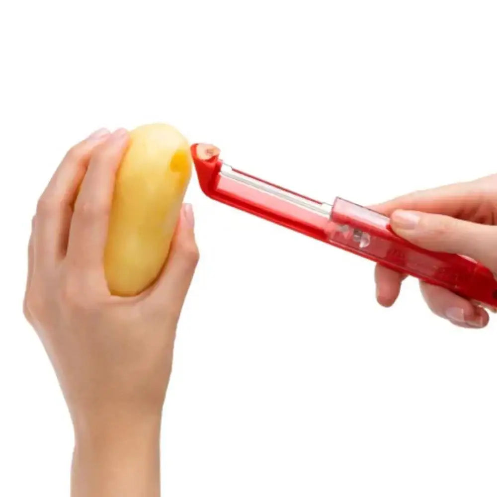 Hand holding a red potato peeler over a yellow potato on a white background