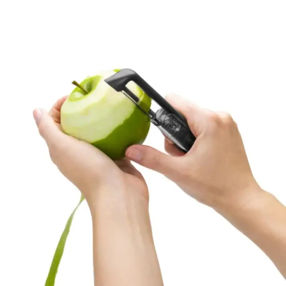 Person using an apple peeler on a green apple with a white background