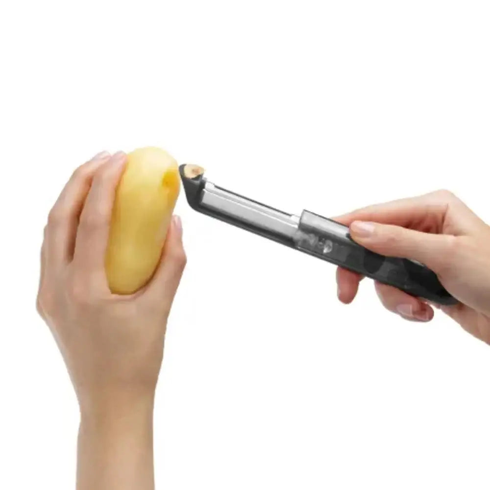 Person using a peeler to cut a potato on a white background