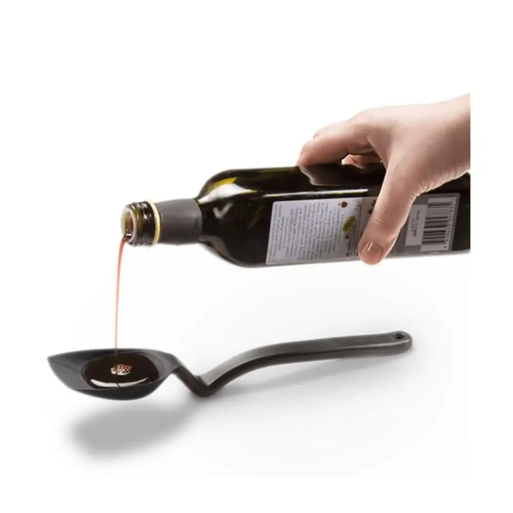 Hand pouring liquid from a bottle into a ladle on a white background