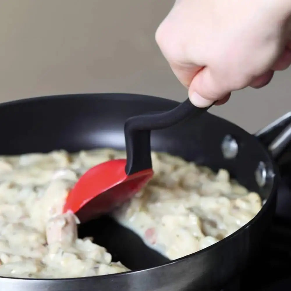 Person using a red spatula to stir food in a pan