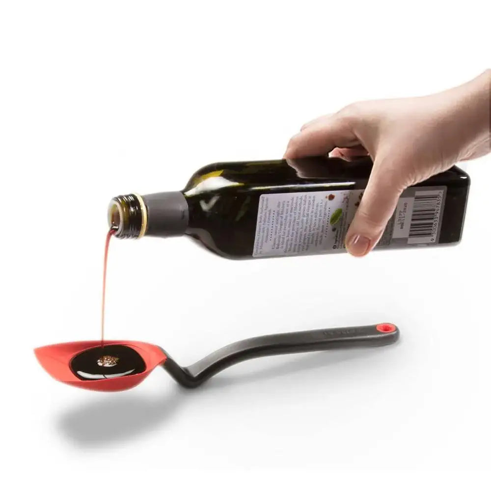 Bottle of olive oil being poured into a red ladle on a white background