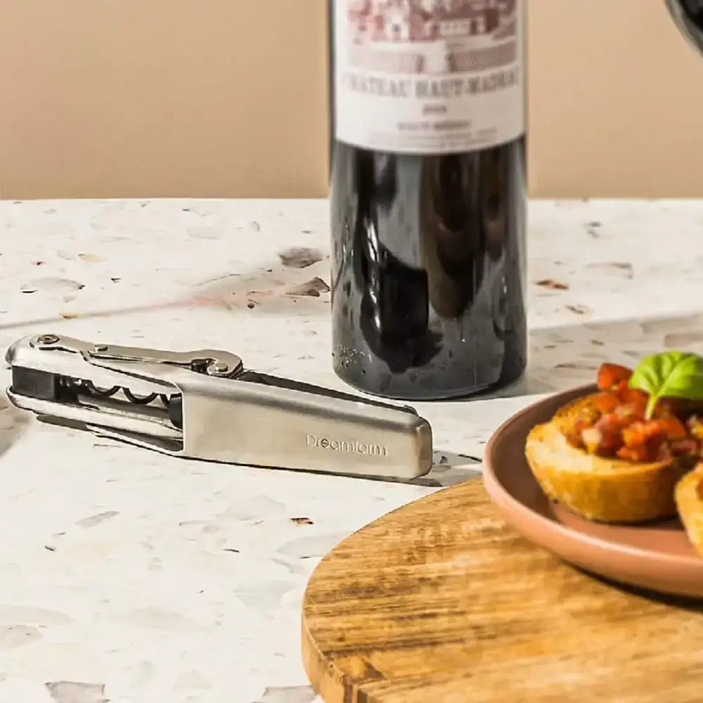Dreamfarm mechanical wine opener on terrazzo kitchen countertop with wine bottle and appetizers at Cookin Stores