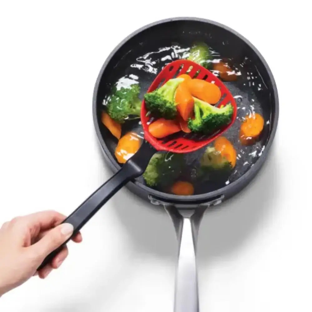 Frying pan with vegetables and a red spatula, on a white background