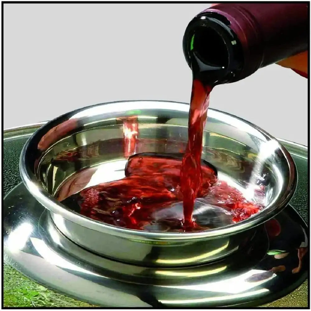 Red liquid being poured from a bottle into a metallic bowl on a gray background