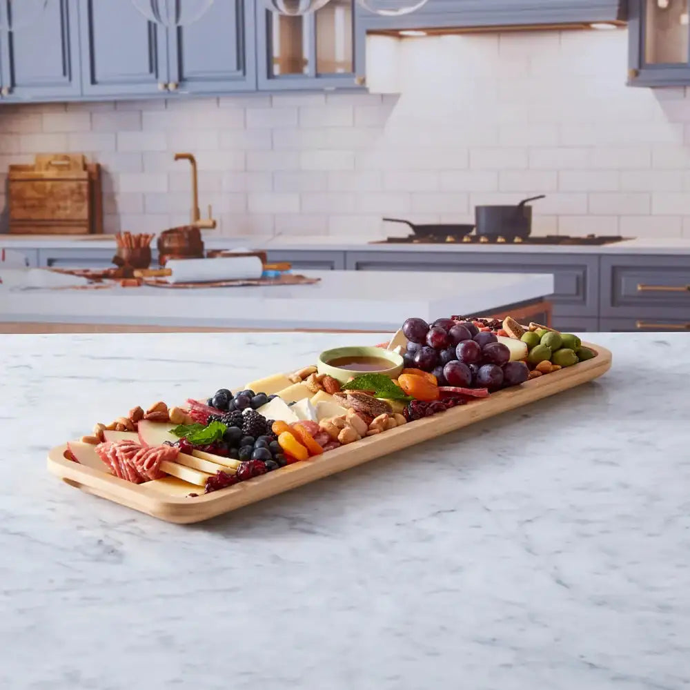 Wooden charcuterie board with assorted meats, cheeses, and fruits on a kitchen counter.