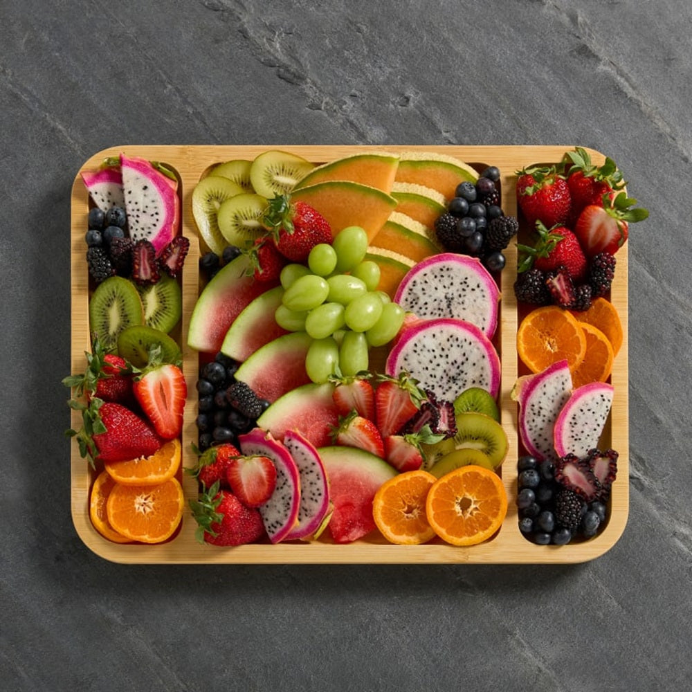 Assorted fruits on a wooden tray with a gray slate background