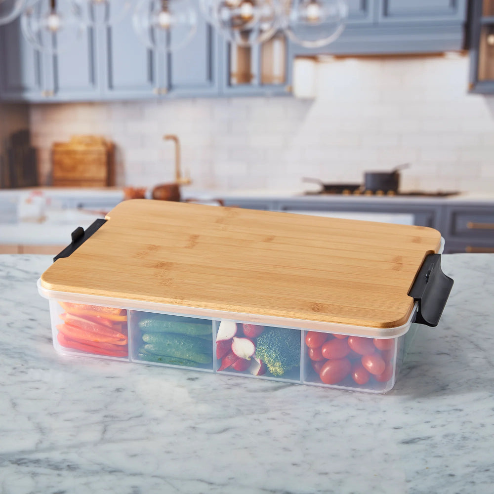 Bamboo cutting board with a transparent container holding vegetables on a kitchen counter.