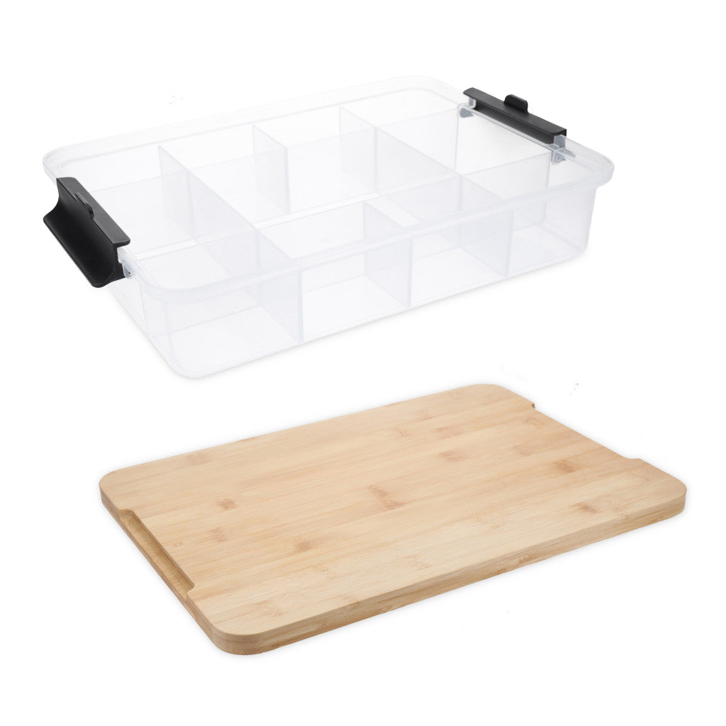 A clear plastic multi-compartment storage organizer box with black handles, shown above a rectangular bamboo cutting board on a white background.