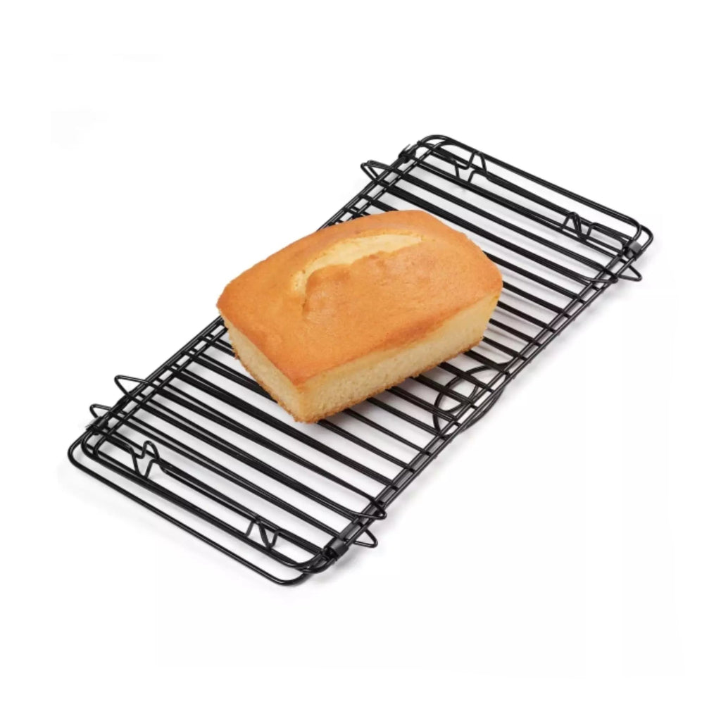 Folded cooling rack with a cake cooling on it on a white background