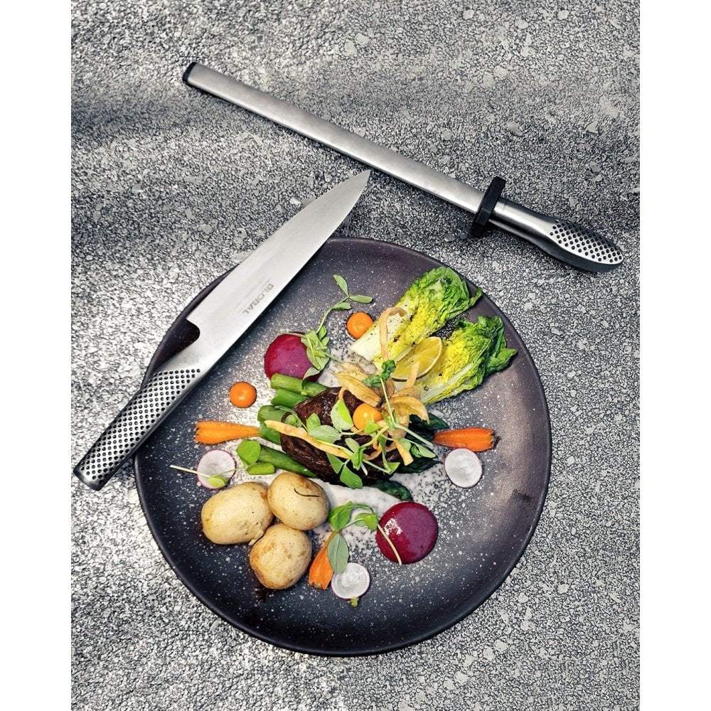 Knife and vegetable peeler on a plate with a colorful salad