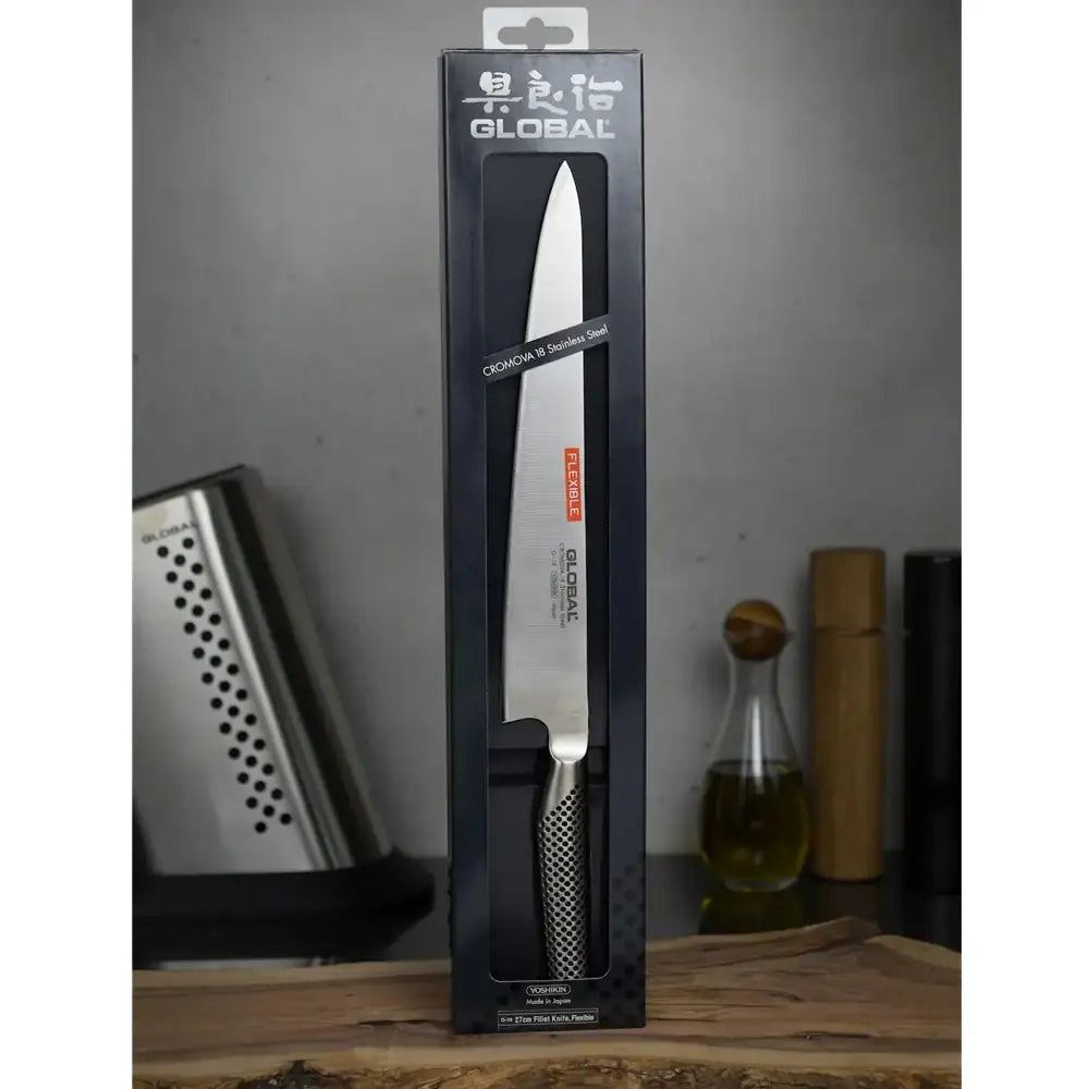 Global brand knife in packaging on a wooden surface with a gray background