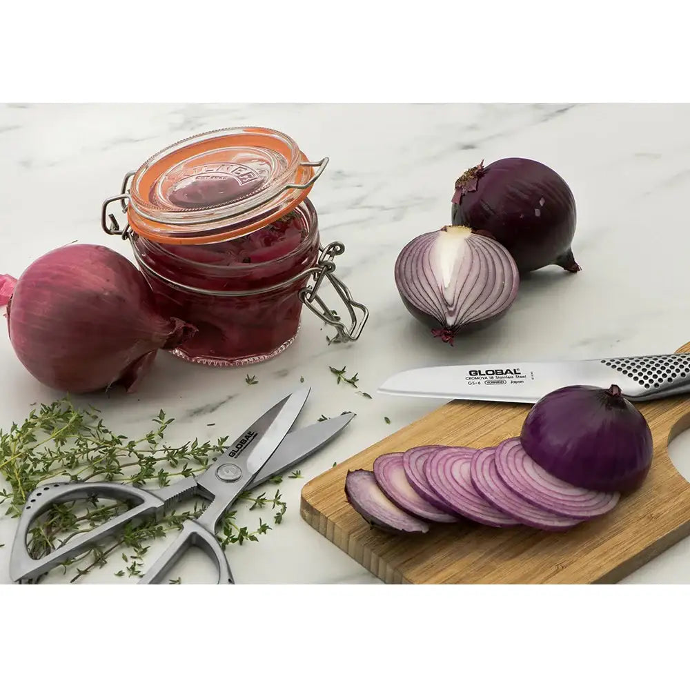 Sliced red onions on a cutting board with a jar of pickled onions and a knife.