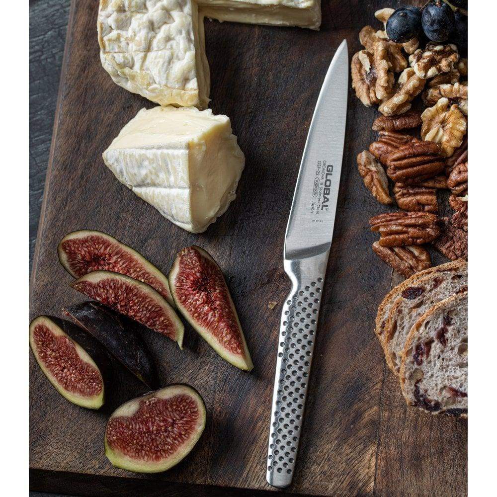 Knife on a wooden board with cheese, figs, nuts, and bread