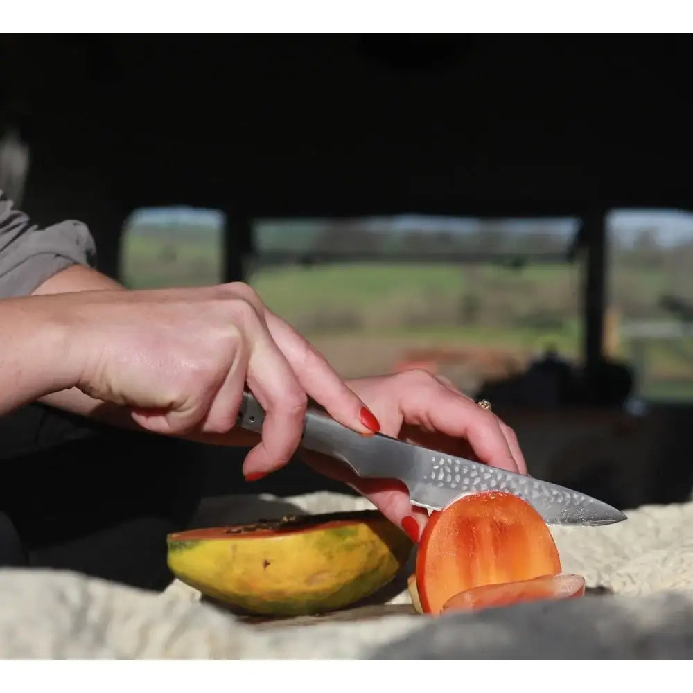 Person cutting a fruit with a knife outdoors