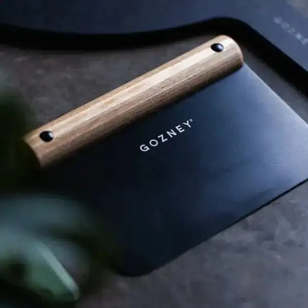 Gozney pizza dough cutter with wooden handle on dark kitchen surface at Cookin Stores