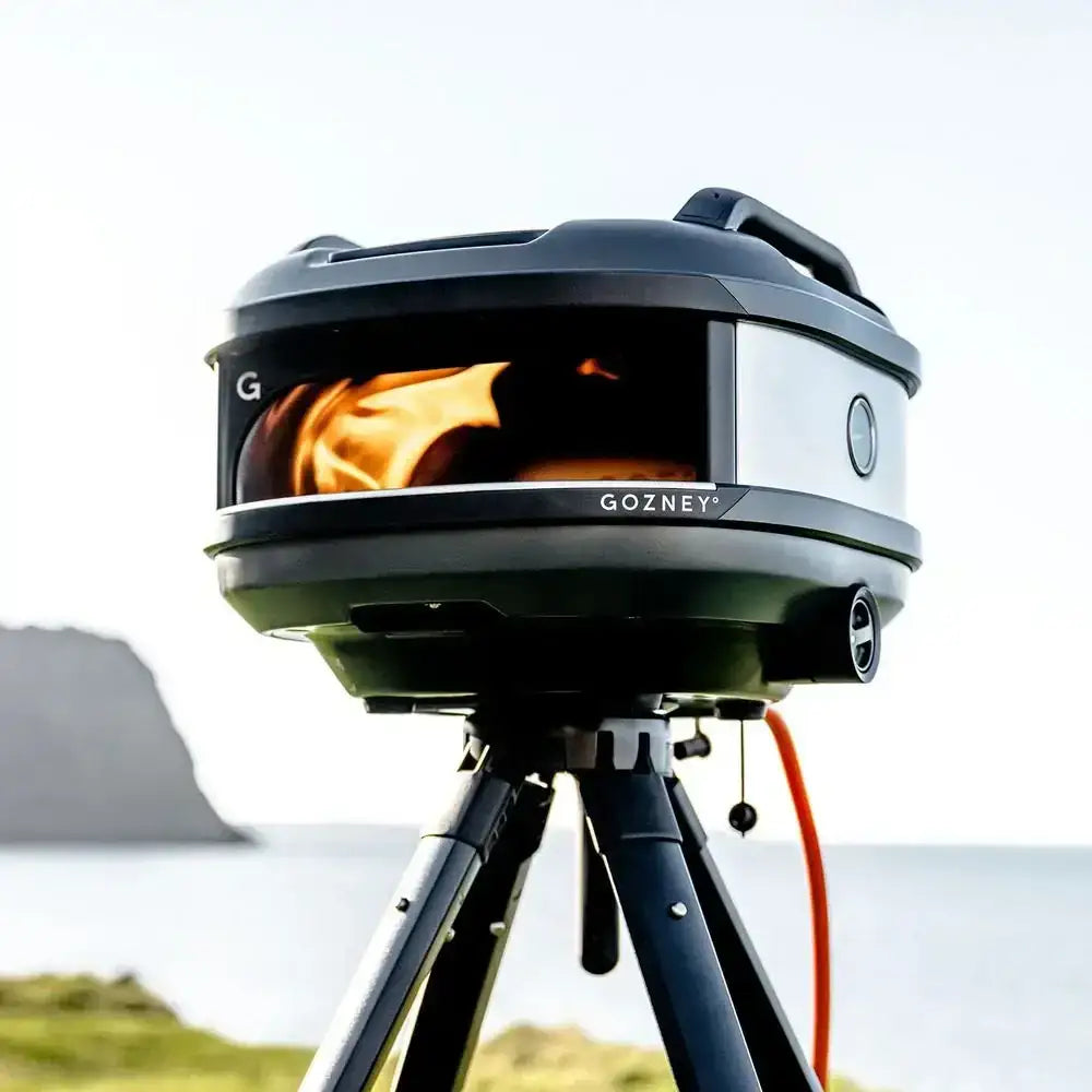 Gozney Tread portable outdoor pizza oven on tripod by water, premium kitchenware at Cookin Stores
