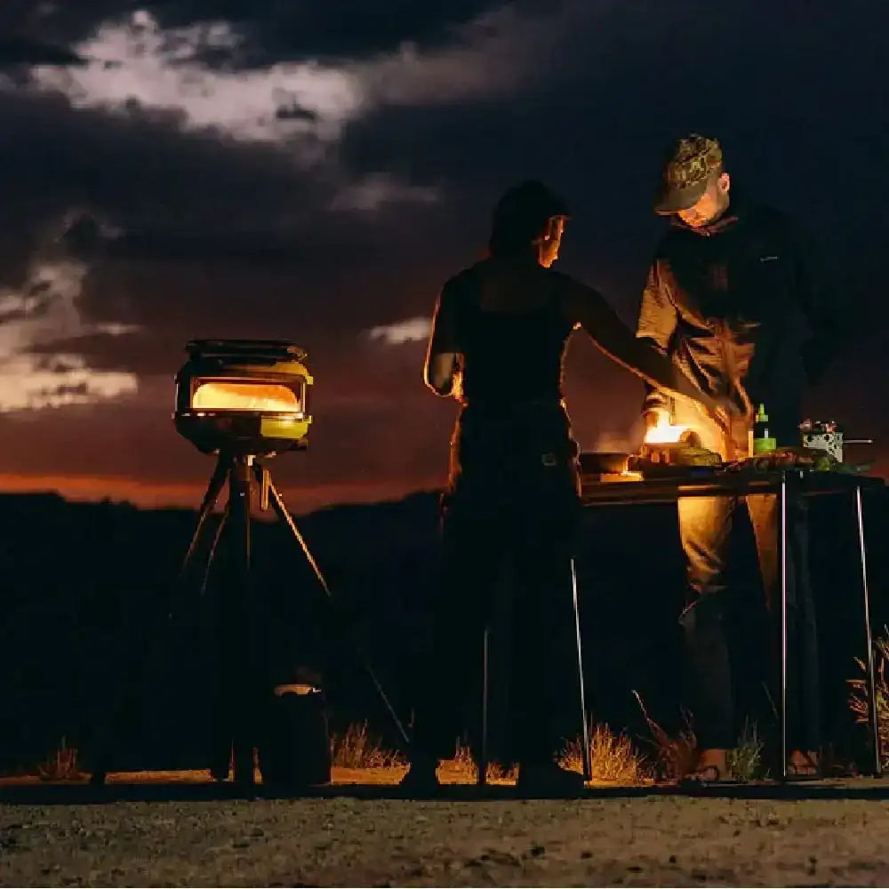 Outdoor pizza oven cooking at sunset, two people preparing food, premium kitchenware scene