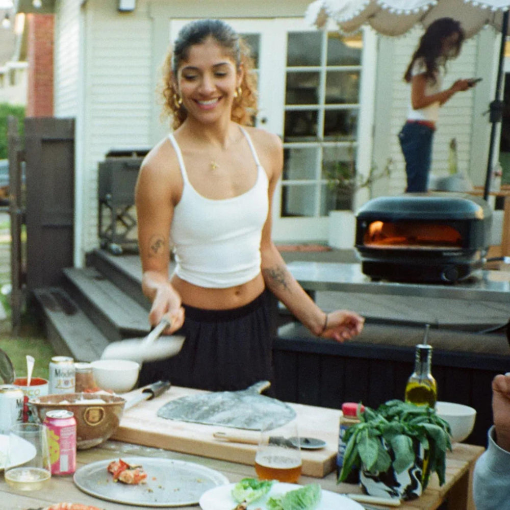 Woman grilling outdoors with a pizza on a pan