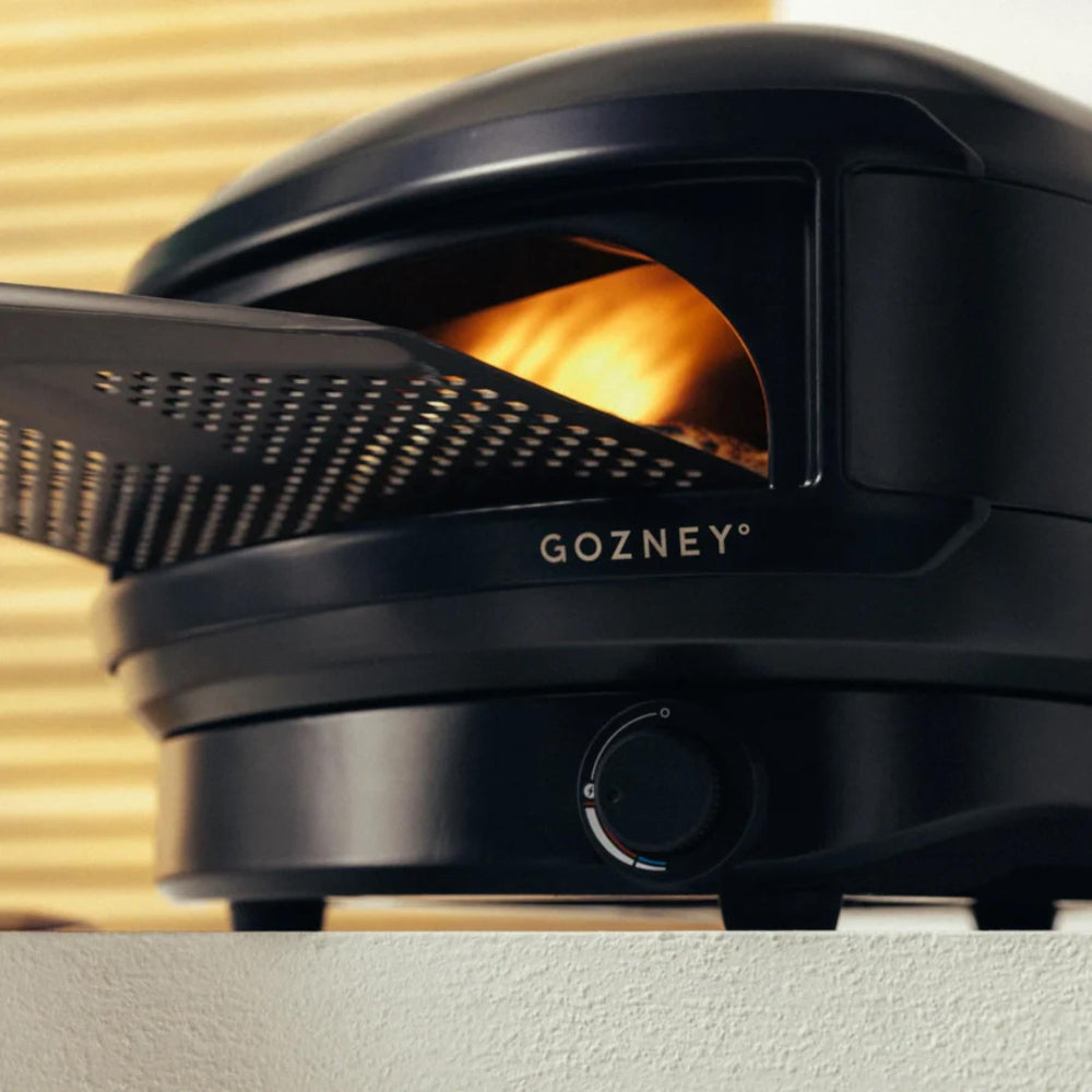 Black Gozney oven with a pizza inside, set against a neutral background