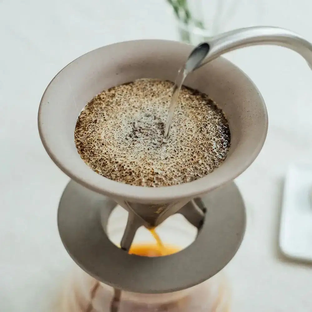 Coffee being poured into a white ceramic filter basket.