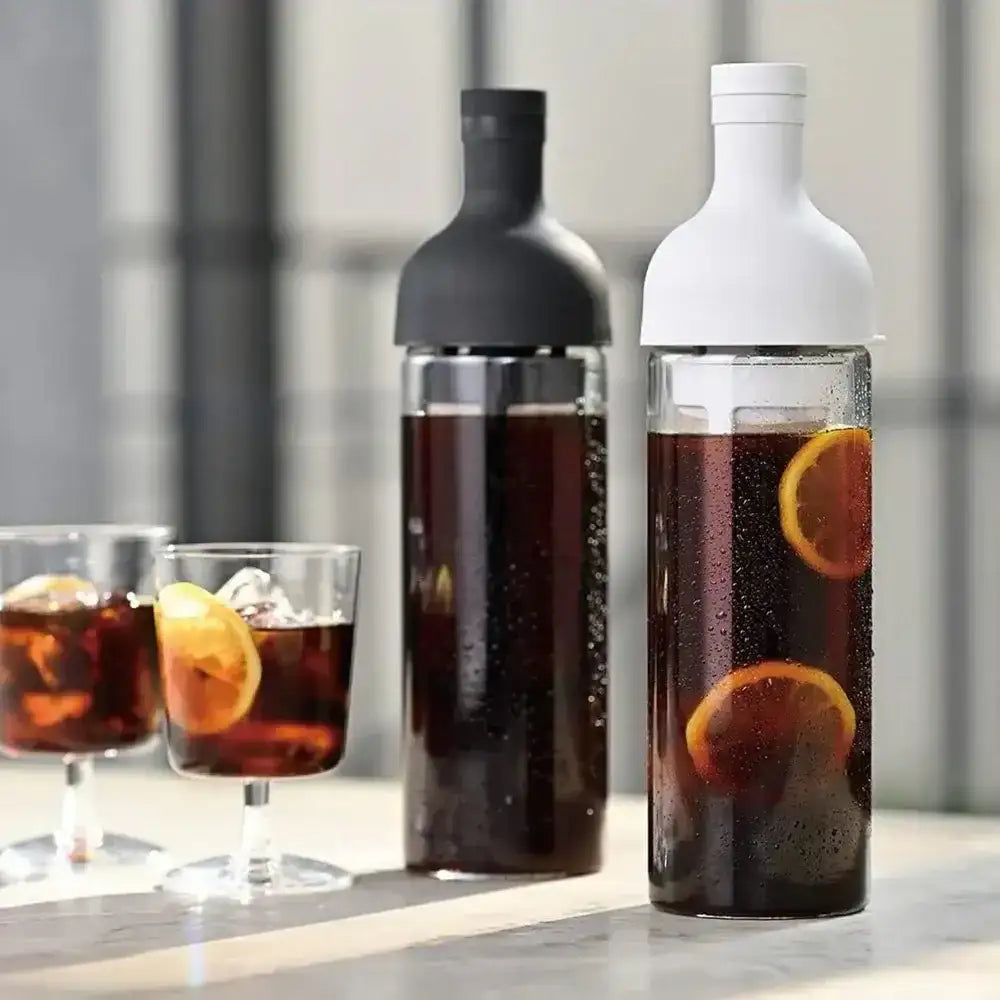 Hario filter-in coffee bottles with black and white caps, filled with iced coffee and lemon slices, on a modern kitchen countertop at Cookin Stores.
