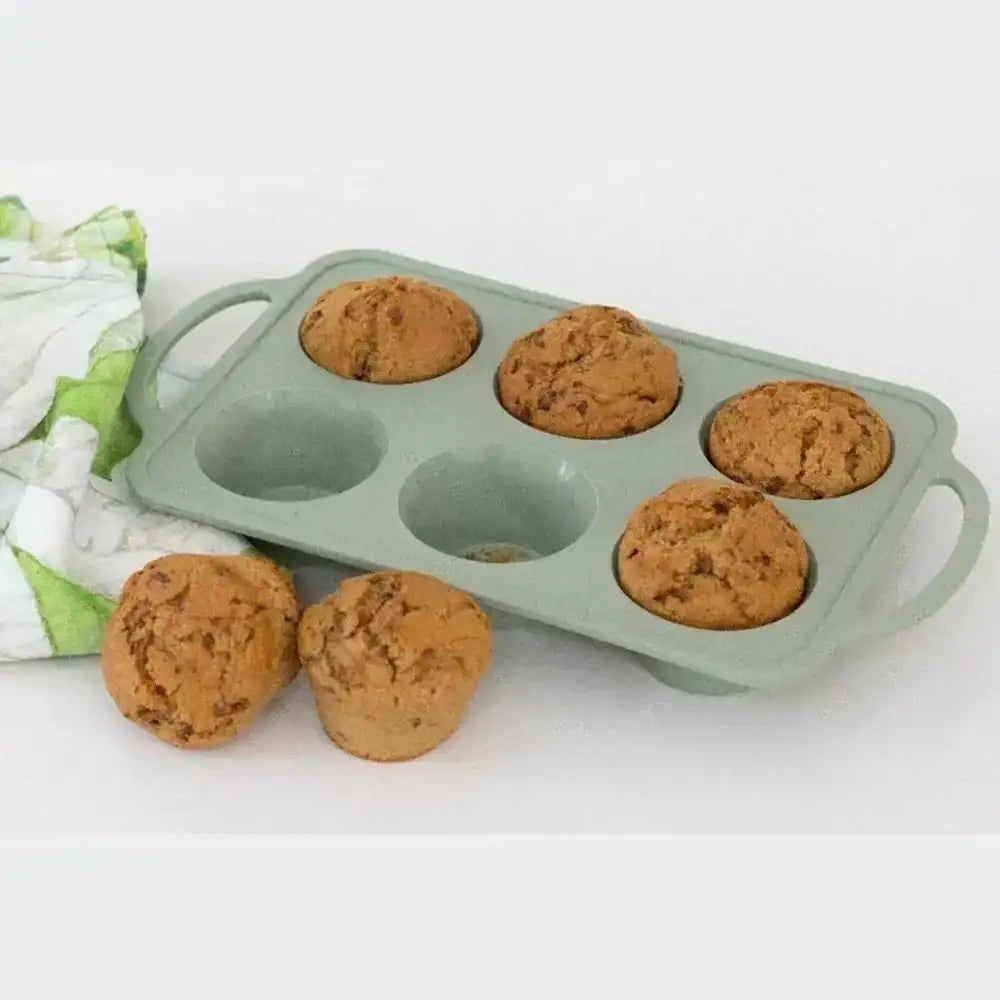 Green muffin tin with baked muffins on a white background