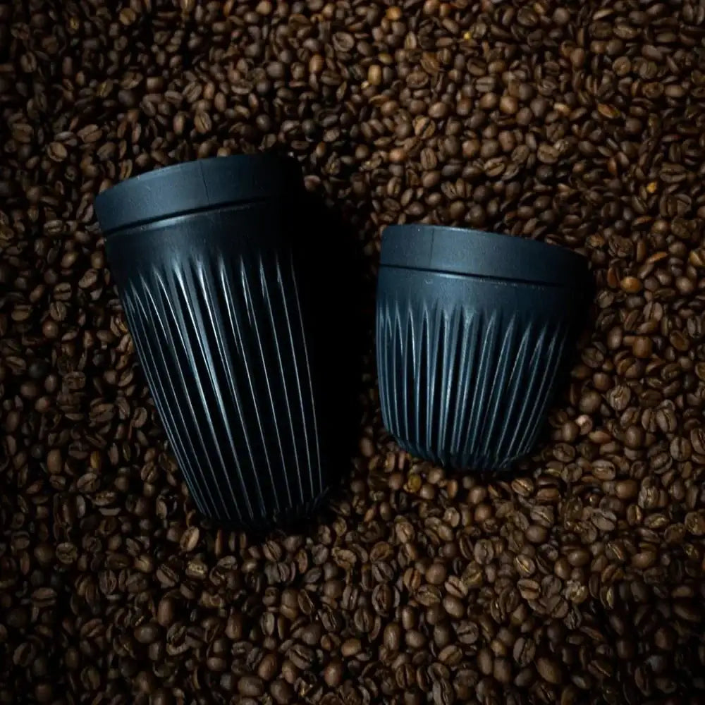 Two blue ceramic cups on a bed of coffee beans