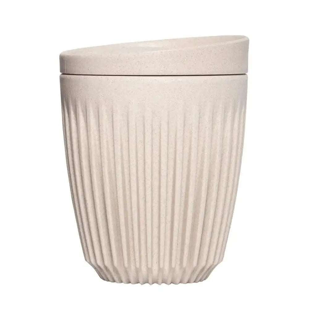 Beige textured coffee cup and lid on a white background