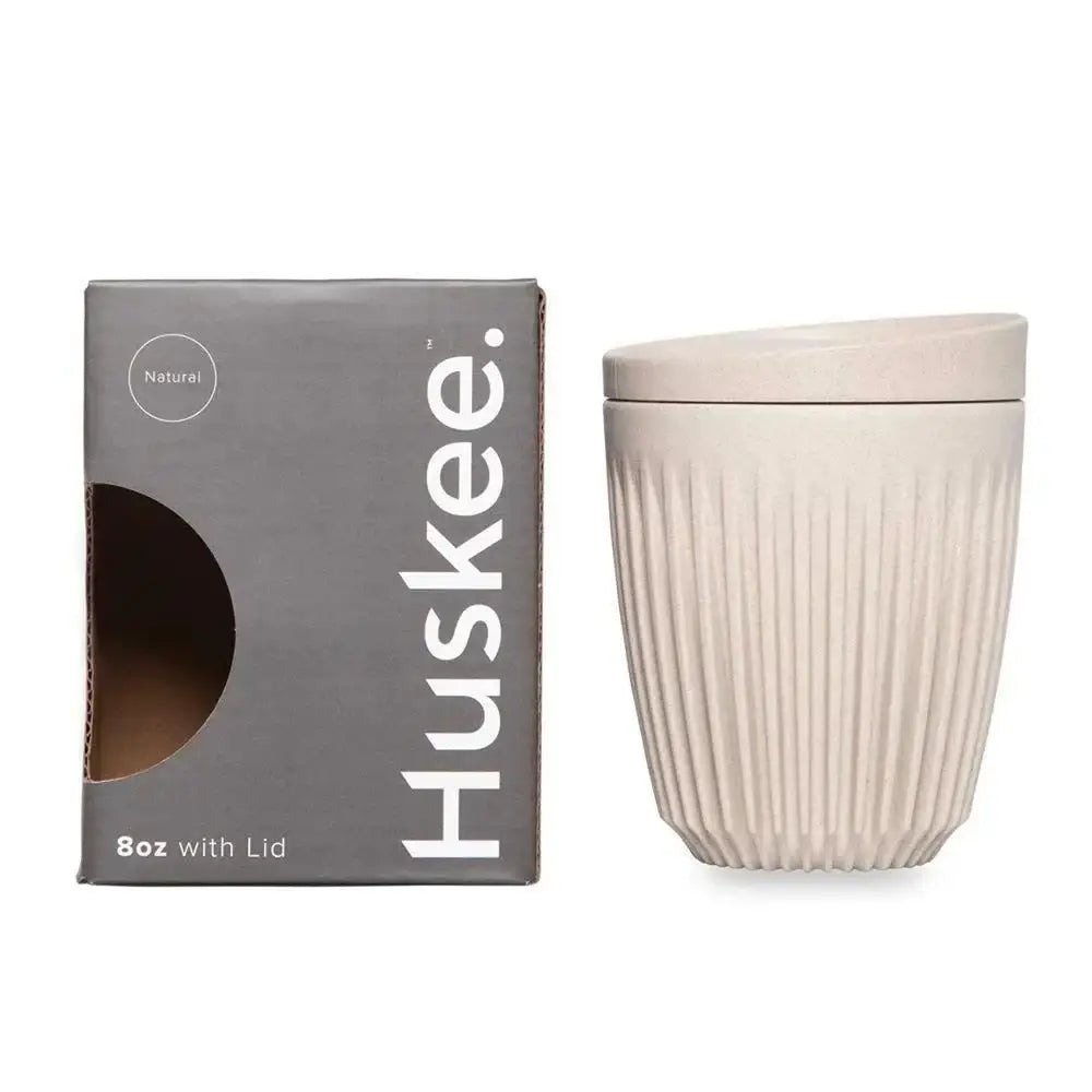 Beige ceramic cup with lid and Huskee packaging on a white background
