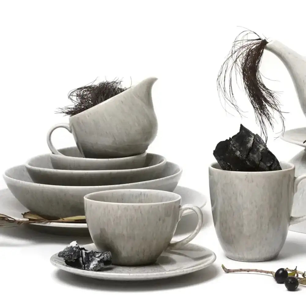 Set of gray ceramic tea cups, saucers, and teapot on a white background
