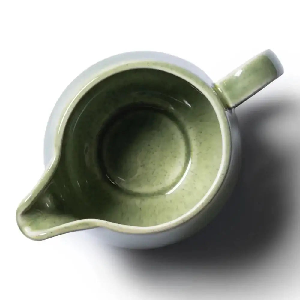 Green ceramic pitcher on a white background