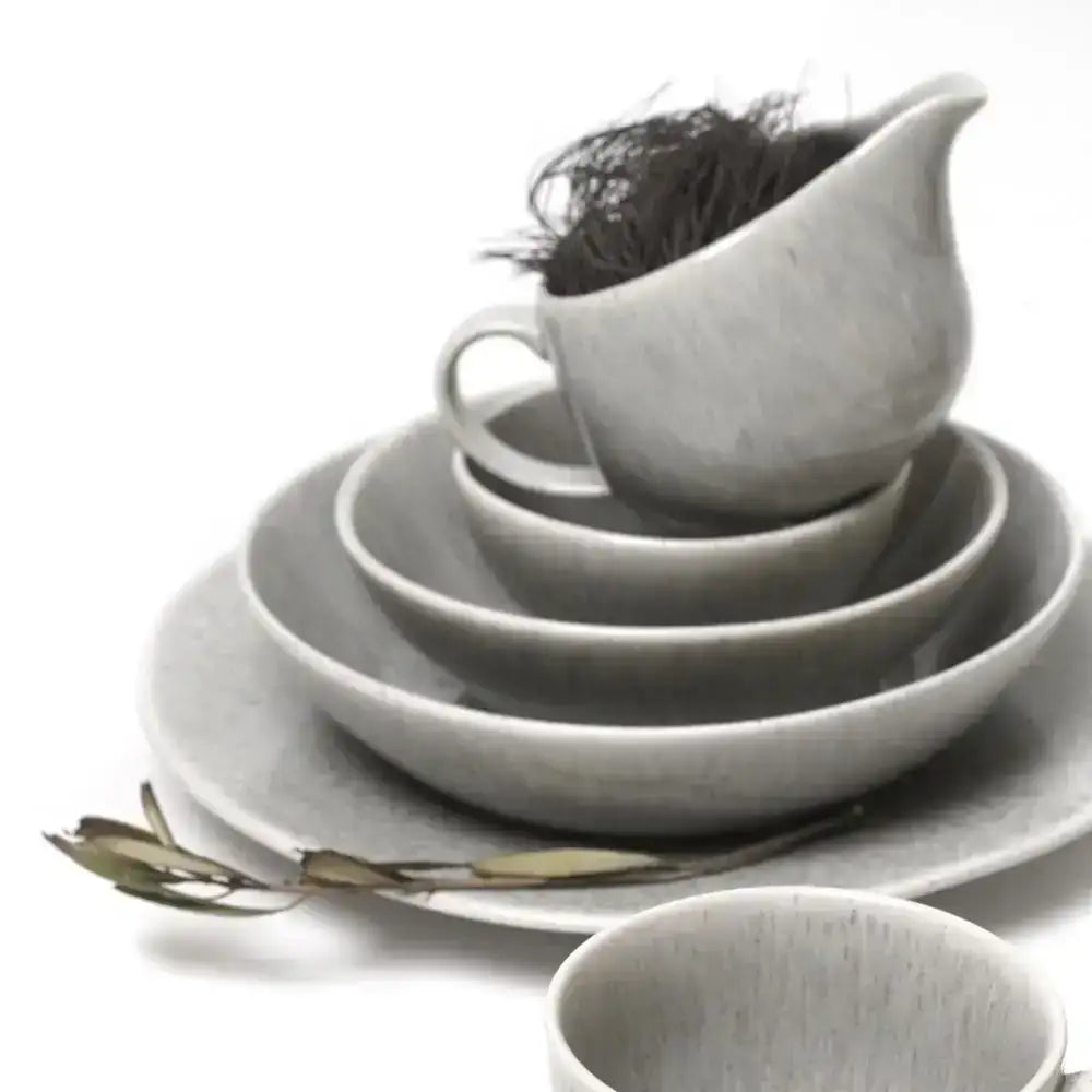 Set of gray ceramic dishes including bowls and a cup on a white background
