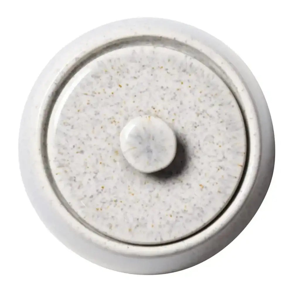 Round ceramic lid from above on a sugar bowl with textured surface on a white background