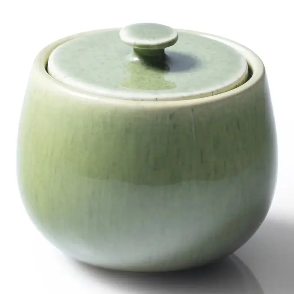 Green ceramic container with a lid on a white background
