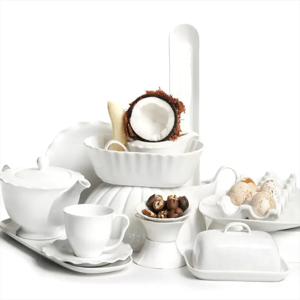 Collection of white ceramic dishes with small food items on a white background