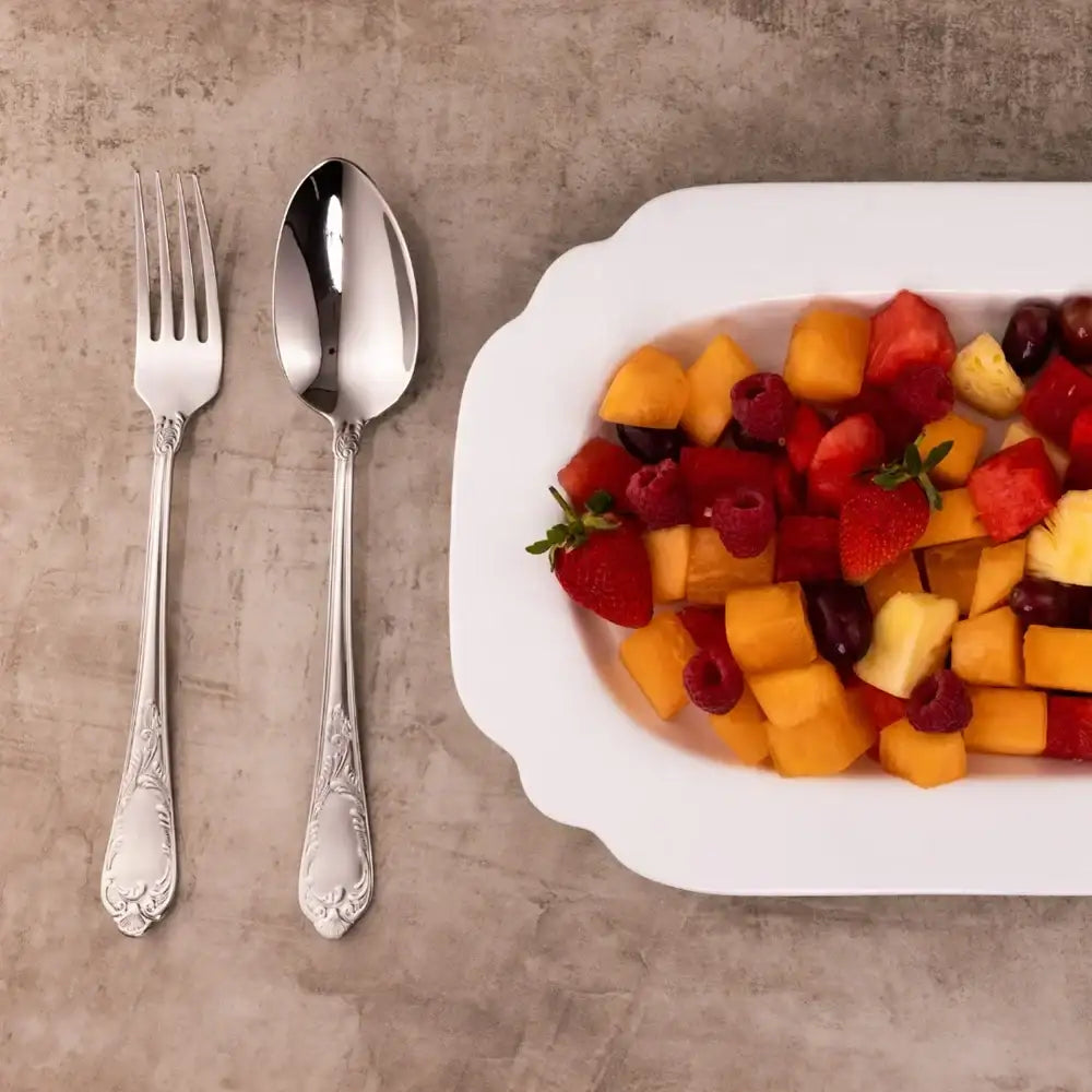 Fork, spoon, and plate of fruit on a textured surface