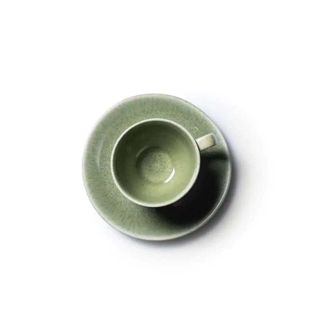 Green ceramic cup and saucer on a white background