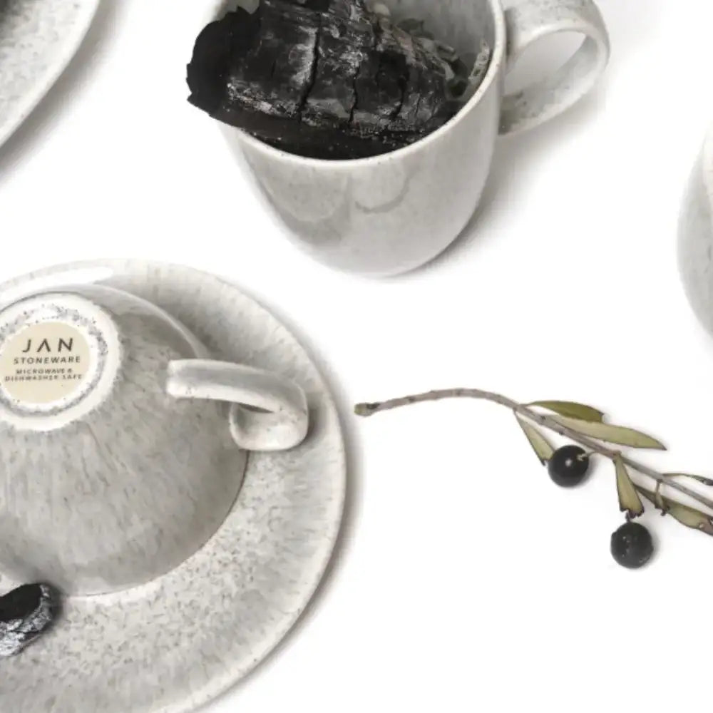 Two gray ceramic cups with handles, one containing a dark substance, on a white surface.