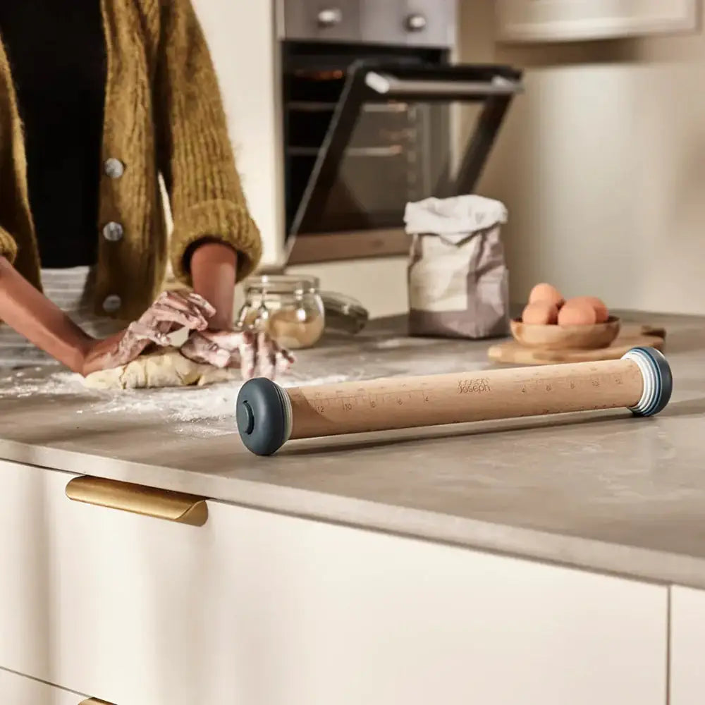 Person kneading dough with a rolling pin on a kitchen counter