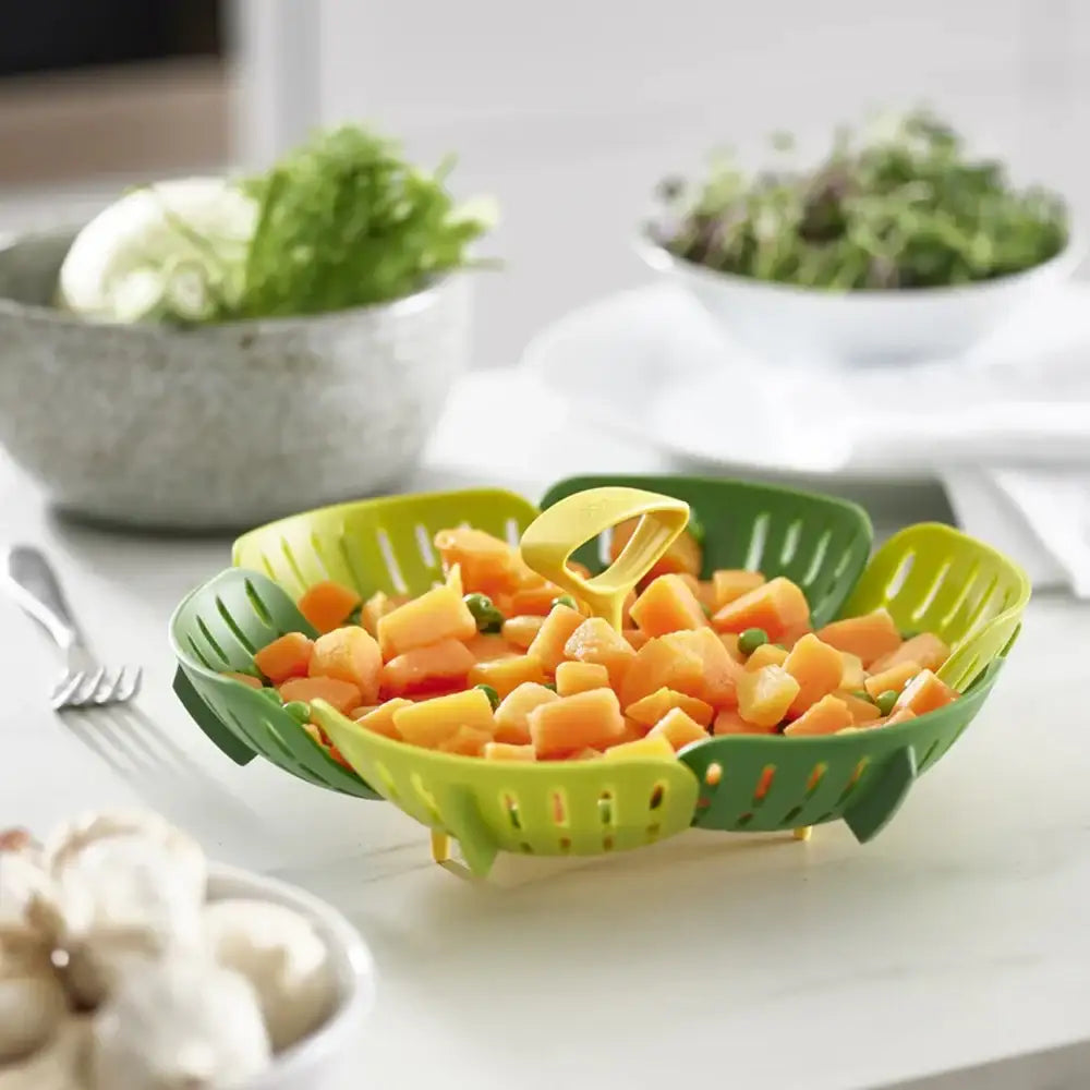 Green kitchen strainer filled with chopped vegetables on a white countertop.