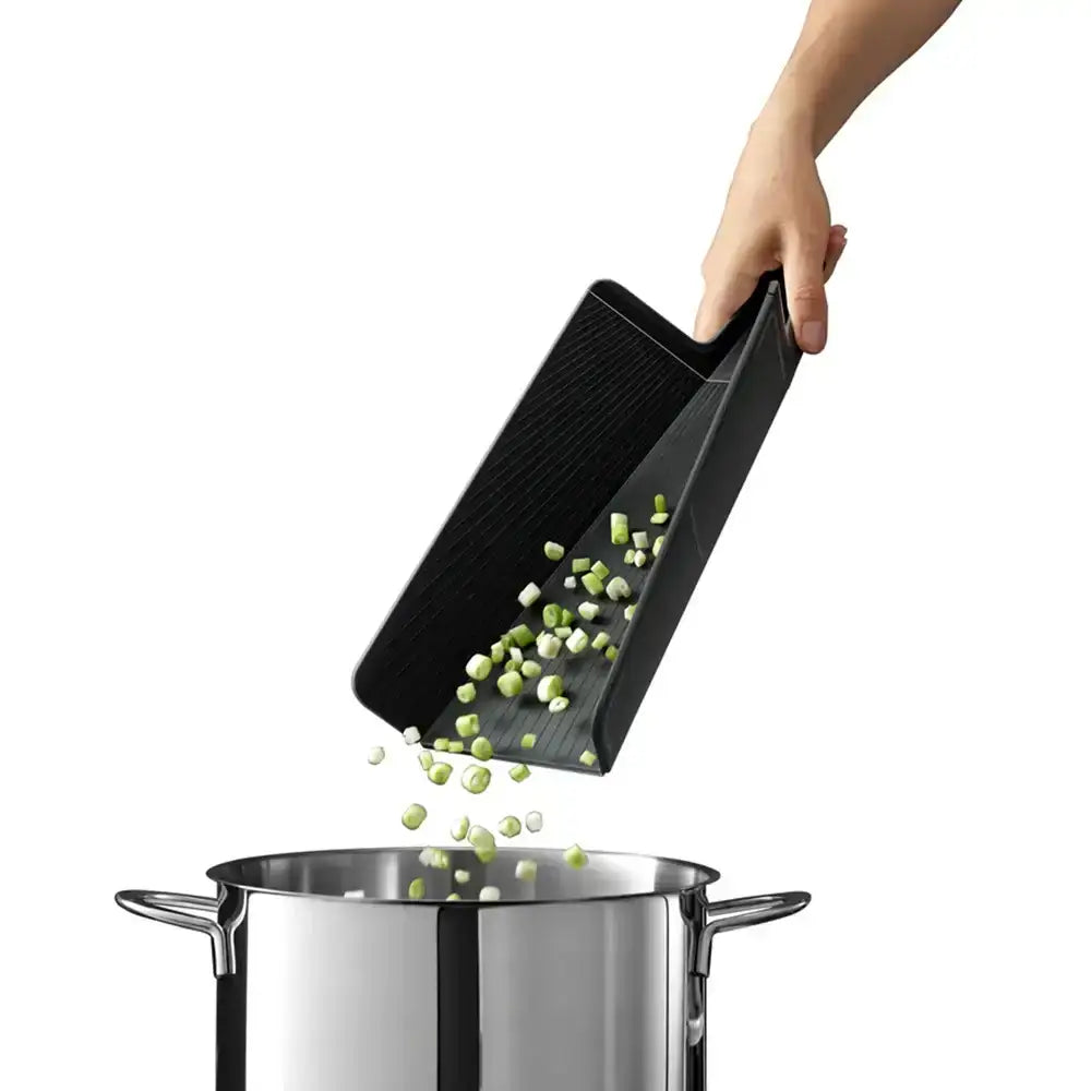 Person using a black slotted spoon to transfer chopped vegetables from a pot.
