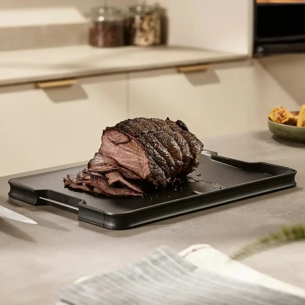Roasted beef on a black grill pan in a kitchen setting