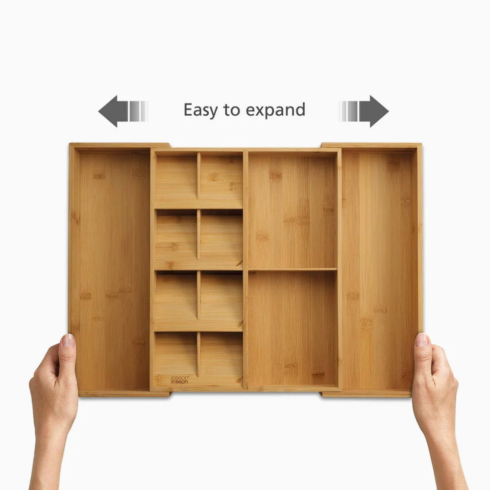 A bamboo organizer tray with multiple compartments, held open by two hands against a white background, with arrows and the text 'Easy to expand' above it.