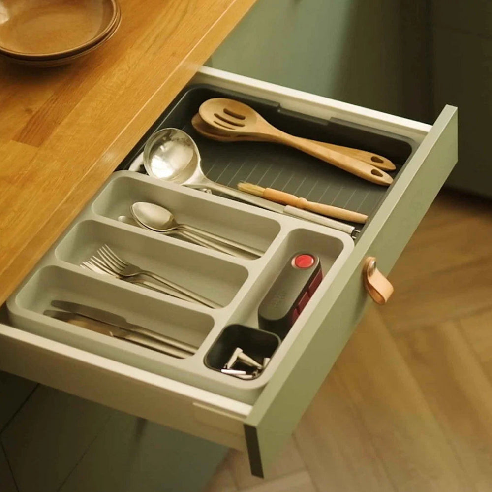 Open kitchen drawer with utensils and cutlery organizer on a wooden countertop.