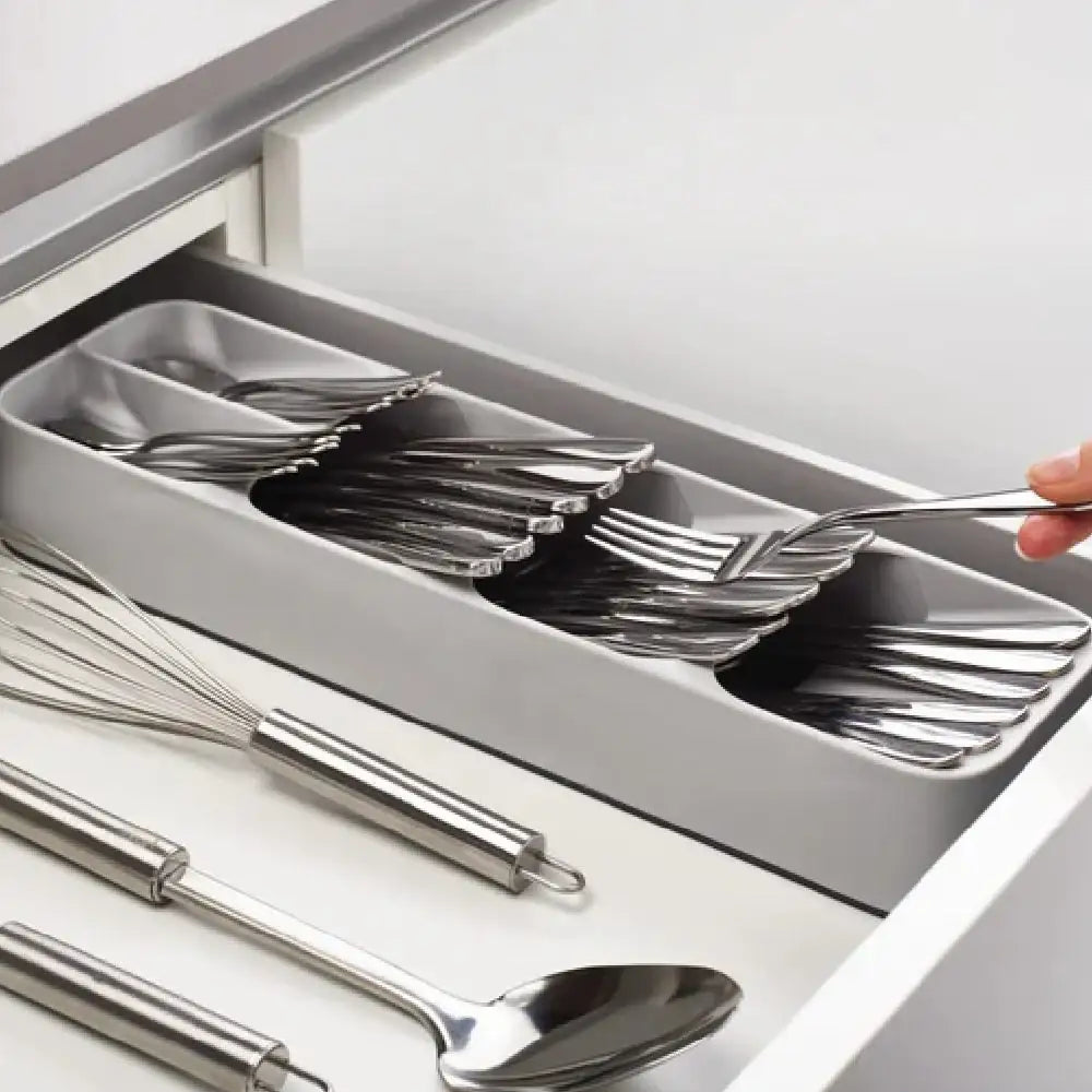 Grey compact cutlery drawer organizer holding stacked forks and spoons in a kitchen drawer
