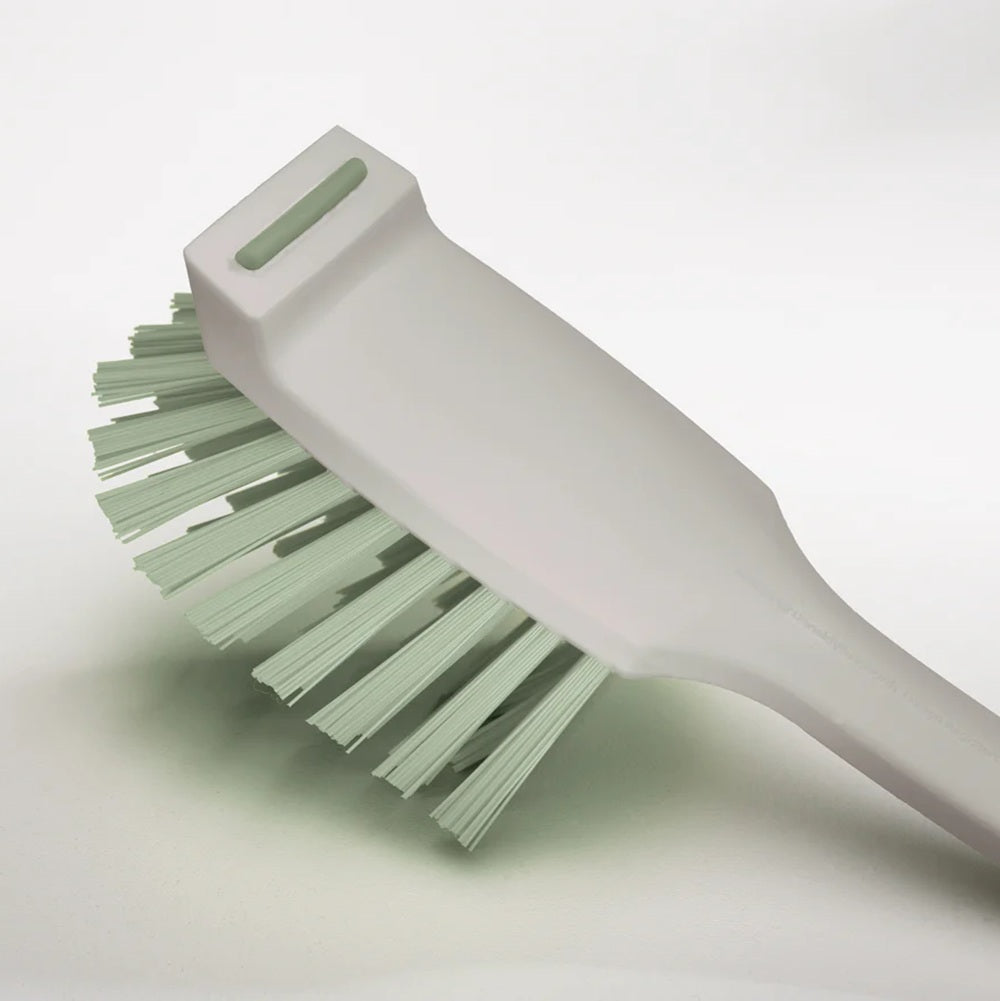 Green brush with a white handle on a light gray background