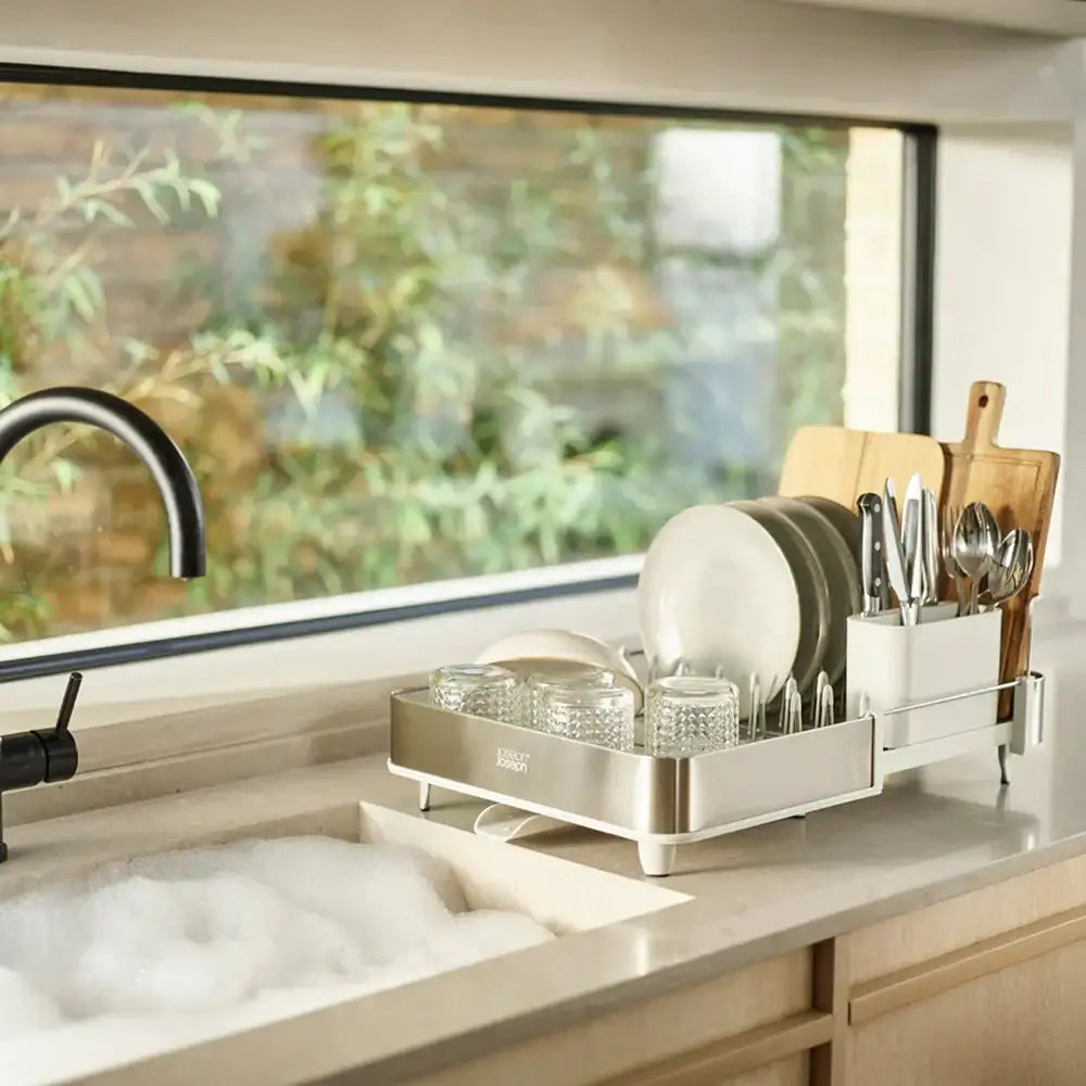 Dish rack with dishes on a kitchen counter next to a window