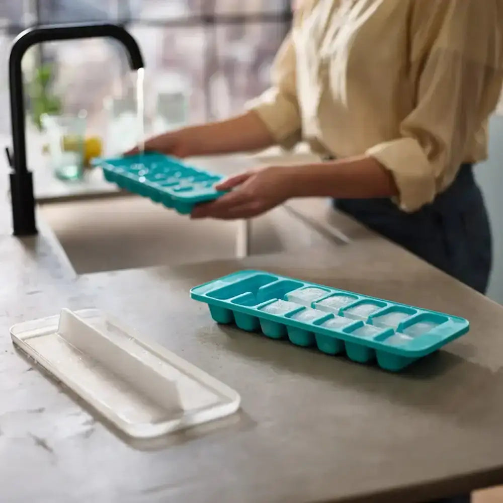 Person holding a teal ice cube tray on a kitchen counter